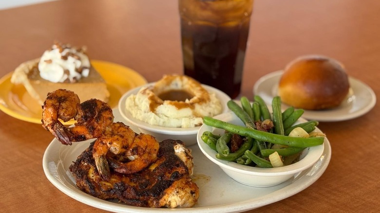 Plate with shrimp, chicken, mashed potatoes, green beans, roll, pie and drink