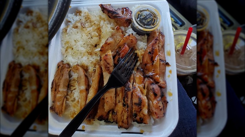 Chicken teriyaki with rice and sauce cup in takeout container