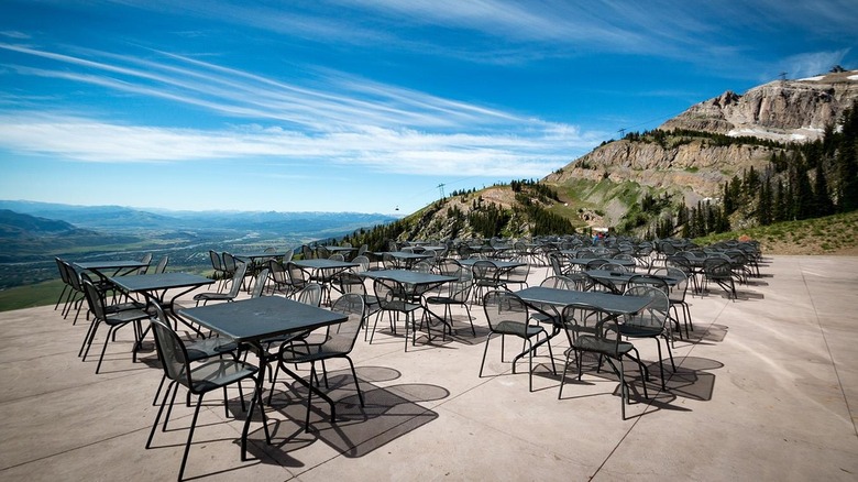 Deck seating with mountain view under blue sky at Piste Mountain Bistro