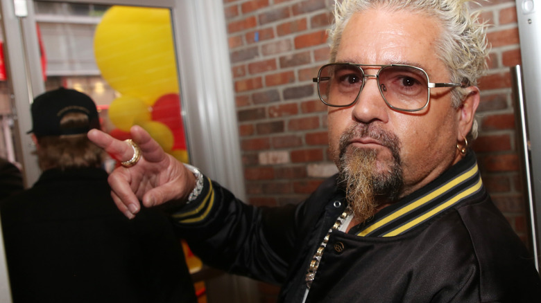Guy Fieri looking over his shoulder brick wall background