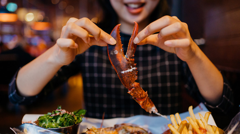 Smiling person holding up lobster claw