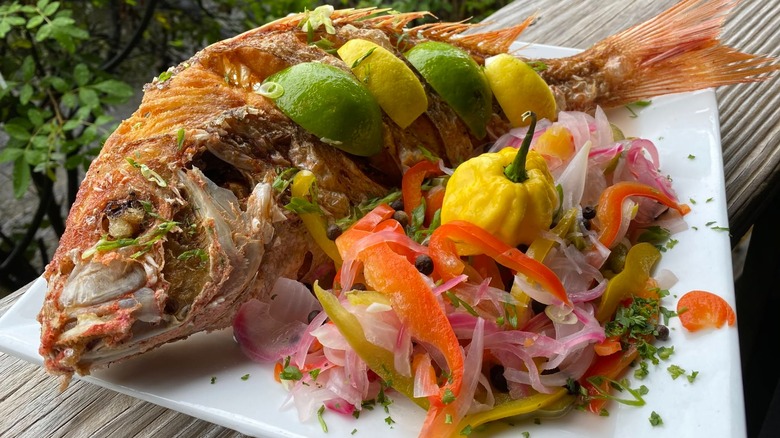 Whole snapper with lemons and limes and pile of fresh veg