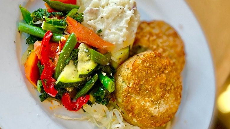 Crab cakes on plate with mashed potatoes and vegetables