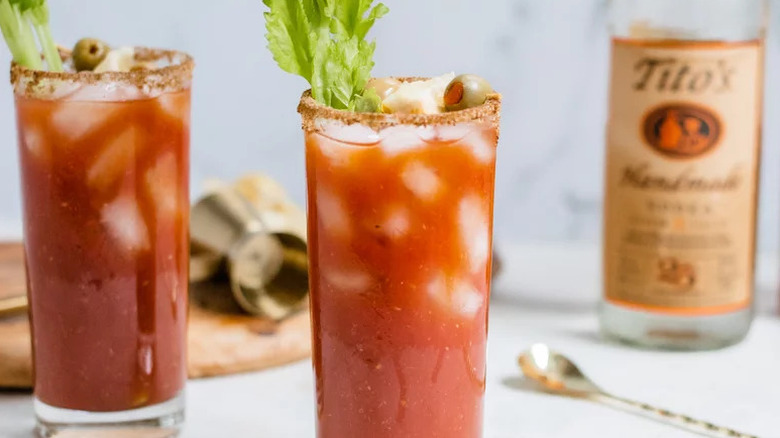 Two Bloody Mary cocktails in glasses, garnished with celery sticks and olives