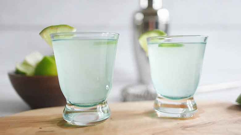 Two spicy jalapeño shots, garnished with lime wedges