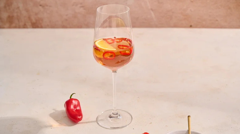 Spicy rosé in glass with sliced red chiles and orange wedge