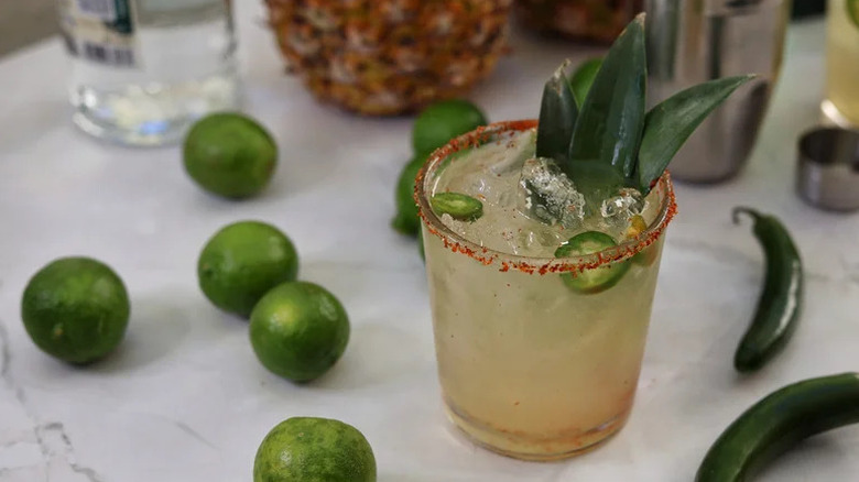 Spicy pineapple margarita in glass, garnished with pineapple fronds and chile salt rim