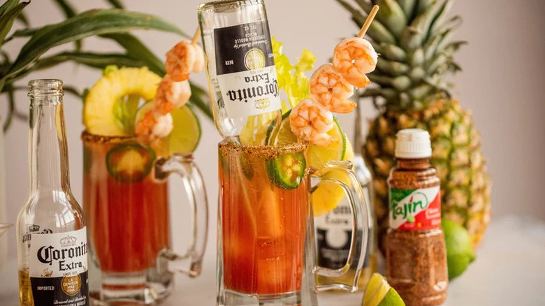 Michelada cocktails garnished with shrimp, lime rounds, pineapple, and jalapeños