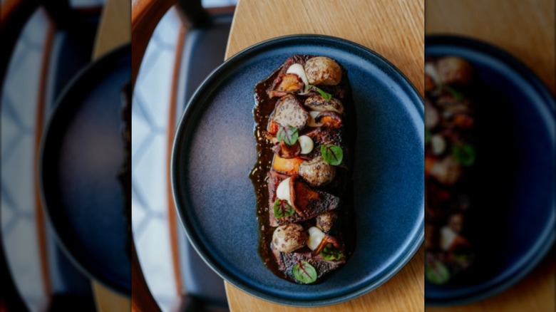 Steak on a blue plate with assorted root veg