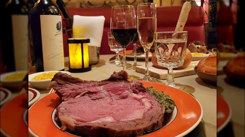 Prime rib on a plate with glasses of wine and a bottle