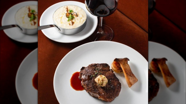 Steak on a white plate with glass of red wine