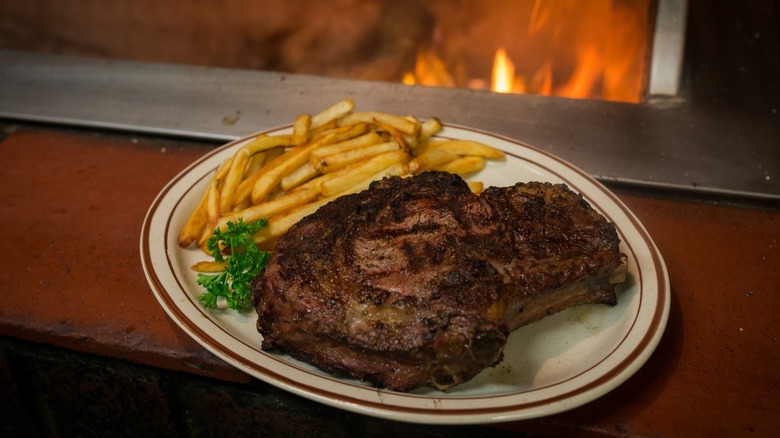 Steak on a plate with fries and fire background