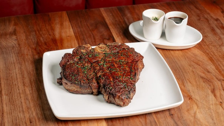 Porterhouse steak on white plate with sauces