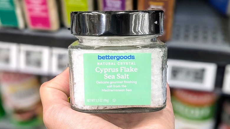 A hand holds a small container of Cyrpus sea salt at Walmart