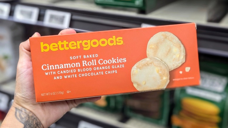 A Hand holding an orange box of bettergoods brand cookies
