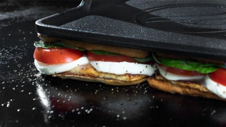 Blackstone Pro Series Griddle Press being used on a panini with tomatoes, basil, and fresh mozzarella on griddle