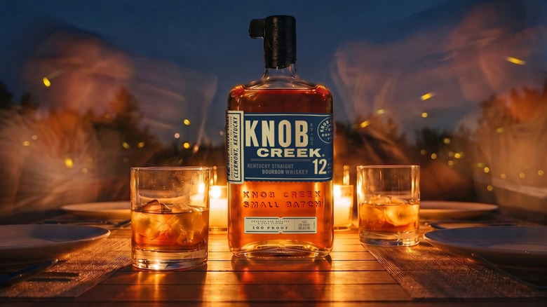 A stylized product shot of Knob Creek 12-year with a blurred candlelit setting in the background