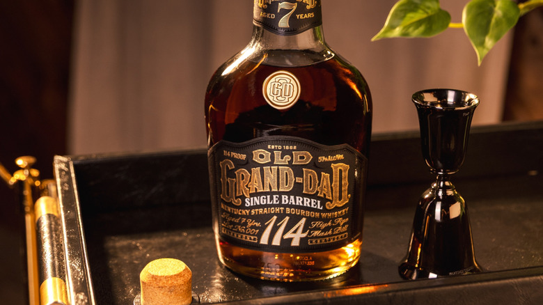 A close-up of Old Grand-Dad 114 bottle on top of a drink cart next to a measuring cup