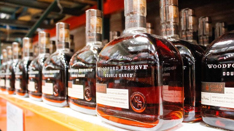 A close-up of a bottle of Woodford Reserve Double Oaked on a liquor store shelf with others shown in the background
