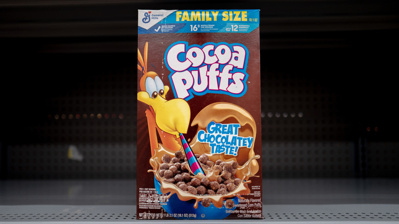 A single box of Cocoa Puffs cereal on an otherwise empty store shelf.