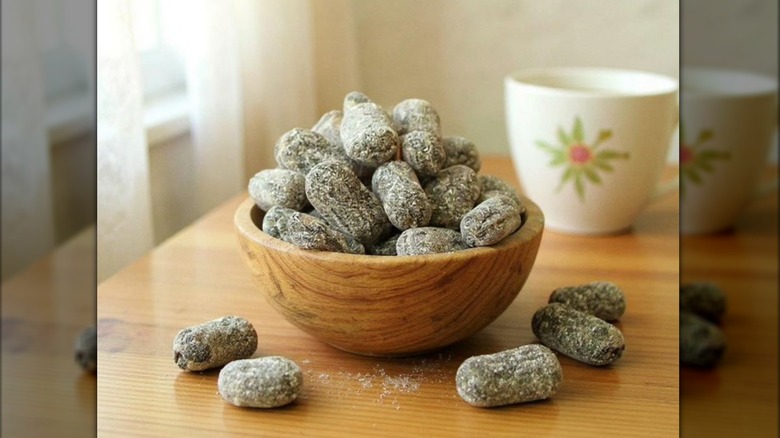 A wooden dish of horehound candies sitting on a table with a cup in the background