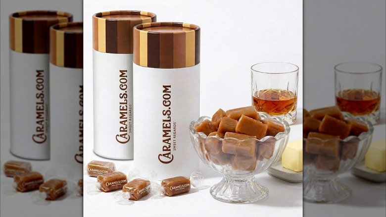 A display of wrapped and unwrapped caramel candy, pictured alongside the branded package and a glass of rum.