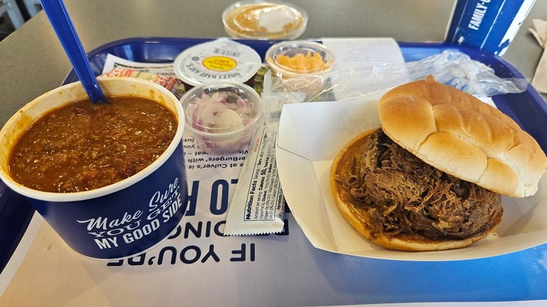 Culver's chili next to a pot roast sandwich with toppings in the background