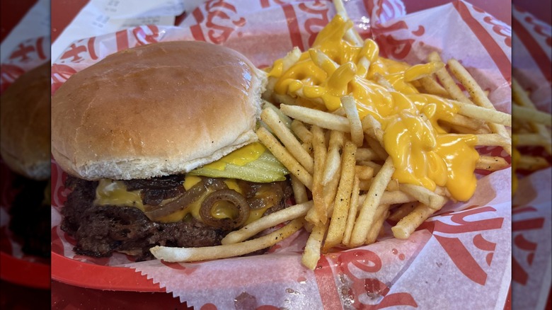 A Freddy's cheeseburger in a basket with some cheese fries