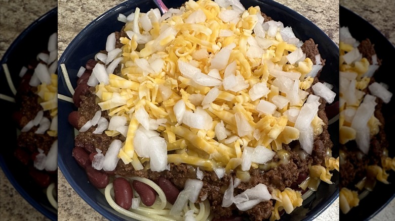 Steak 'n Shake's 5 Way Chili in a bowl topping with cheese and onion, showing ground meat, kidney beans, and spaghetti beneath