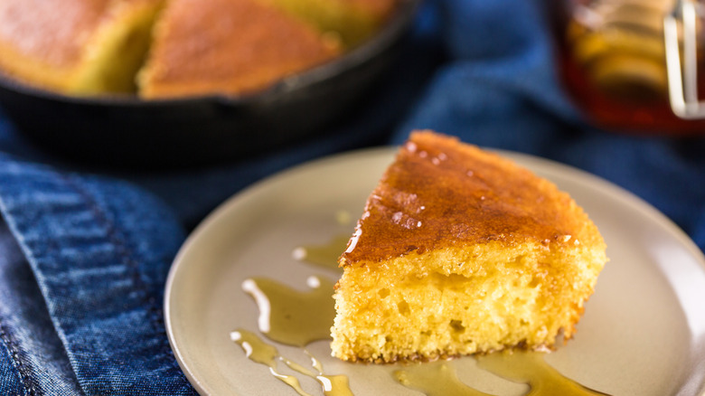 Slice of cornbread with honey drizzled over it on a plate