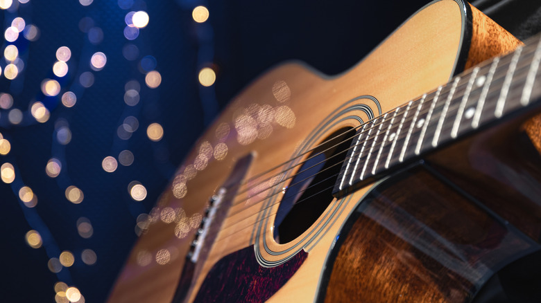 An acoustic guitar up close with twinkly lights in the background