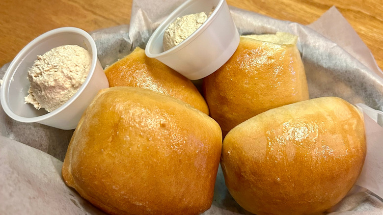 Texas Roadhouse rolls in a basket with containers of whipped butter