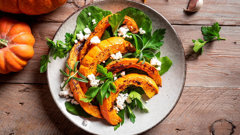 Seasonal autumn salad with pumpkin and greens on a white plate