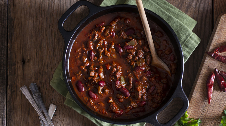 A bowl of chili with beans and rich broth in a skillet
