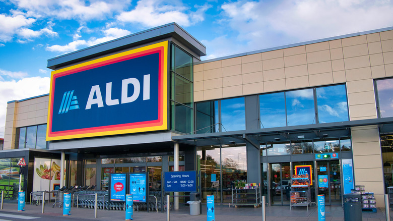 An Aldi storefront in front of a blue, cloudy sky on a bright day