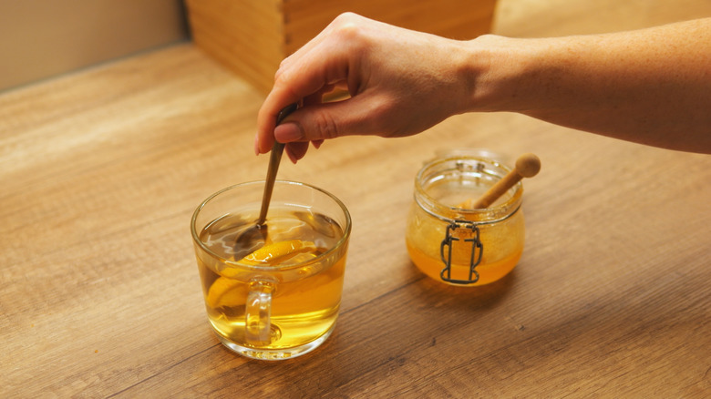 woman stirring honey into tea
