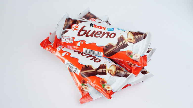 A number of Kinder Bueno chocolate bars piled up against a white background