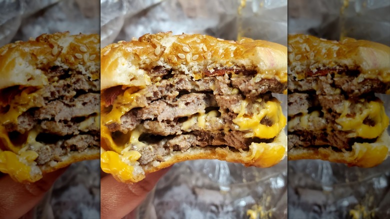 Hand holding Burger King Quad Stacker over paper wrapper