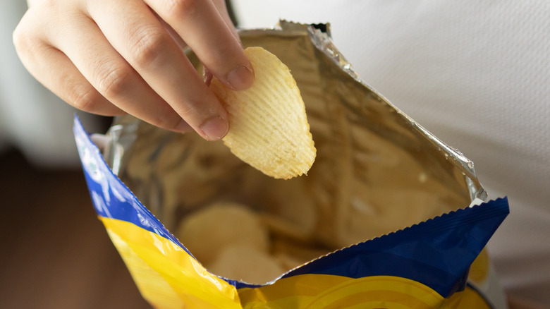 Hand grabbing chip from bag 