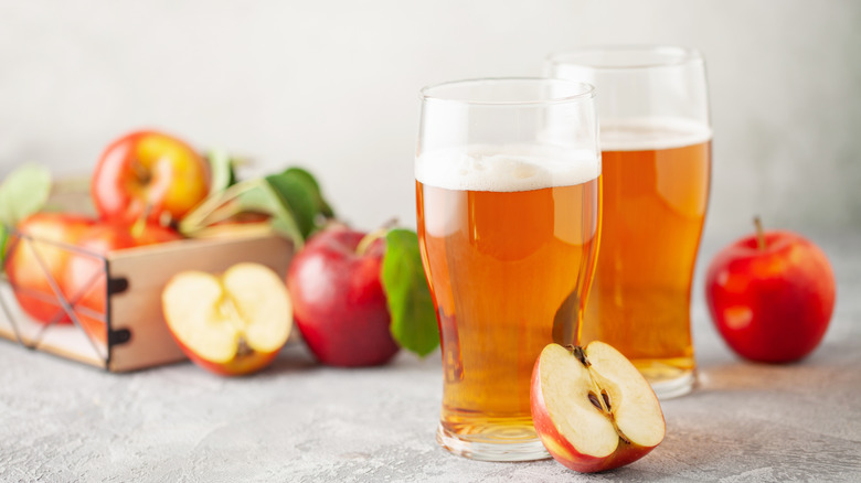 hard apple cider in glasses with fresh apples next to it