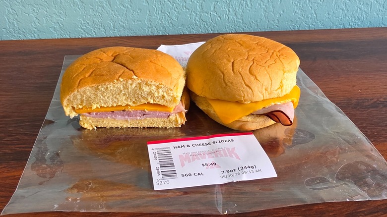 Two ham and cheese sliders on wrapper with one cut