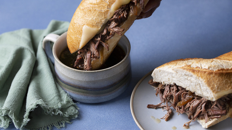 French dip sandwich being dipped in au jus
