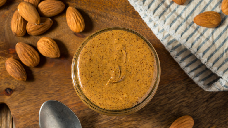overhead view of jar of almond butter with loose almonds
