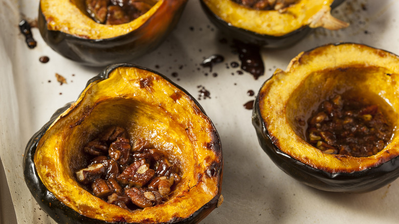 Roasted acorn squash halves filled with walnuts, sitting on parchment