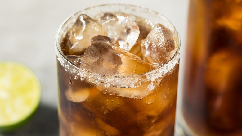 Batanga tequila and cola cocktail with ice in glass with salted rim