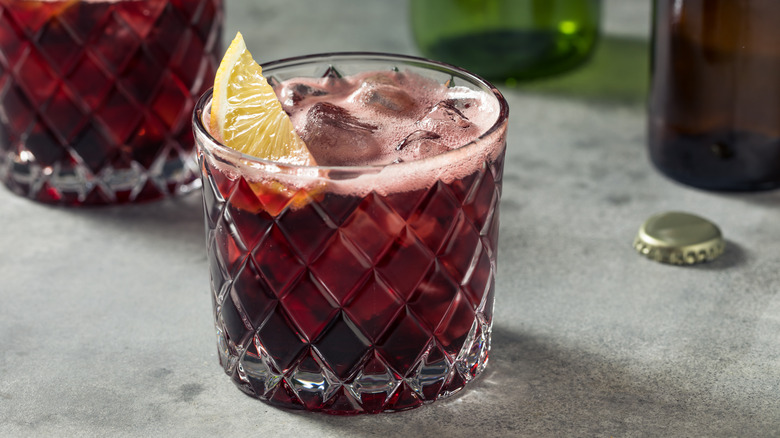 Kalimotxo red wine and cola cocktail in rocks glass with lemon wedge