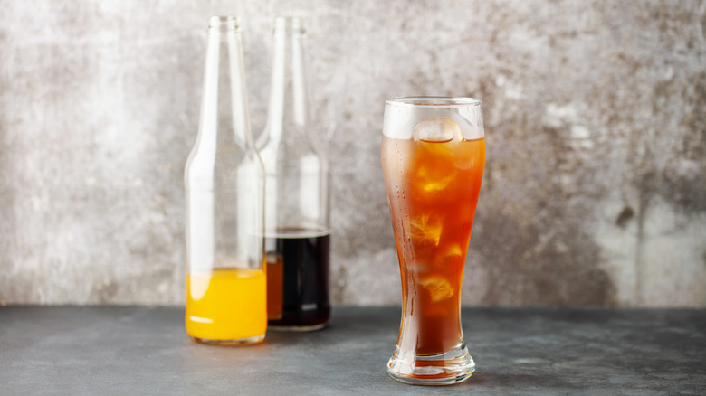 Spezi cocktail in tall beer glass with glass bottles of lemonade and cola in background