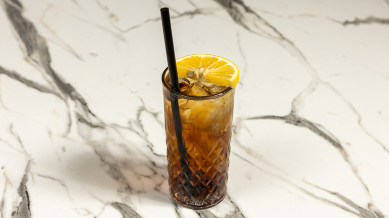 Tennessee Tea in tall glass garnished with half orange wedge with black straw