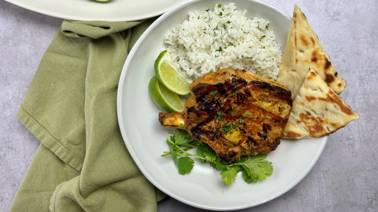 Tandoori pork chop with rice, lime wedges, and naan