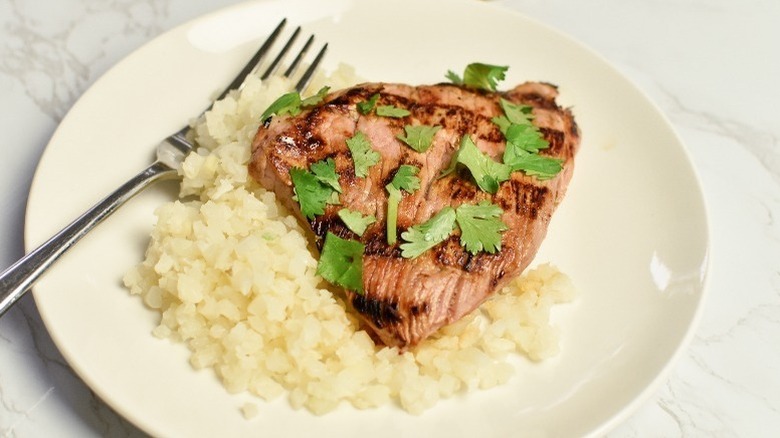 Pork tenderloin slice with rice on plate